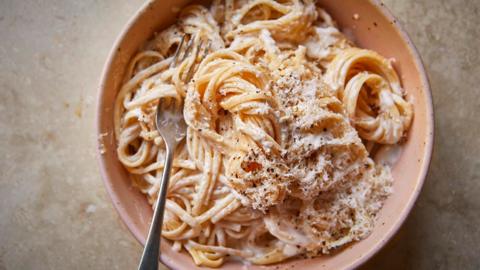 Creamy pasta sauce recipe in a peach bowl on a stone background.