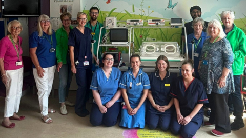 Nurses and doctors standing around the new neonatal transport incubator at Broomfield Hospital in Essex 