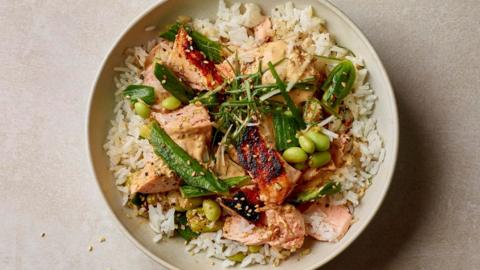 Cooked salmon on a bed of white rice with vegetables