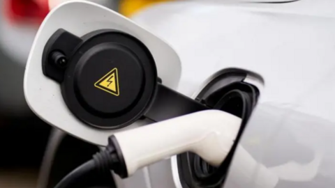 A picture of a white car being charged using an EV charger.