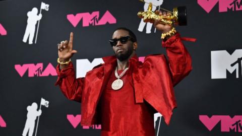 Sean "Diddy" Combs in a red suit posing on red carpet at the 2023 MTV Music Awards.