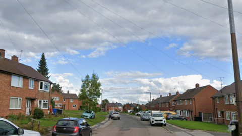 A road with houses either side and blue sky above