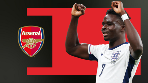 Bukayo Saka, wearing England's white home shirt and holding his arms up in celebration after scoring a goal, against a red and black background and next to the Arsenal club crest