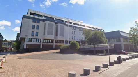 A small courtyard outside a grey and brown court building.