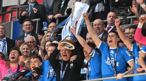 Peterborough manager Darren Ferguson lifts the EFL Trophy, surrounded by his players