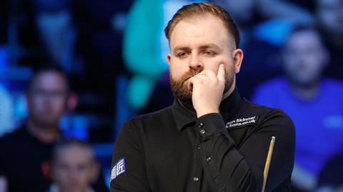 Welsh snooker player Jackson Page contemplates the table with hand to face