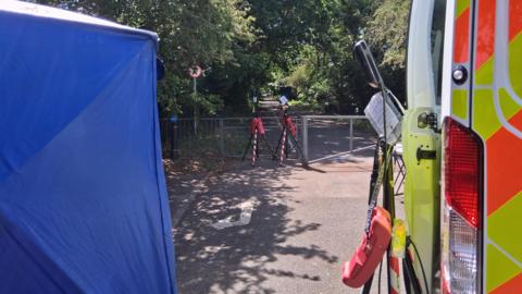 A police tent and van parked near an alleyway where floodlights have been set up.