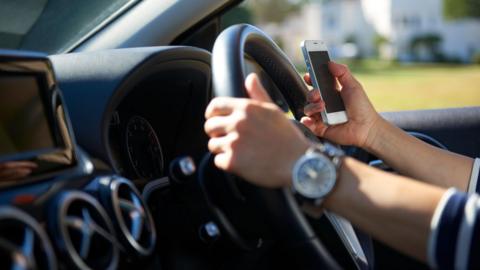 Someone driving their car while looking at their phone