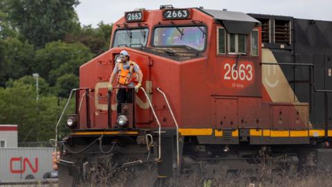 A worker rides on the front of a train at the CN Rail freight depot in Hamilton, Ontario, Canada August 19, 2024.