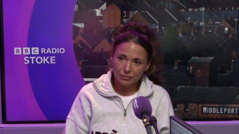 A woman wearing a white jumper sitting down in the BBC Radio Stoke studio.