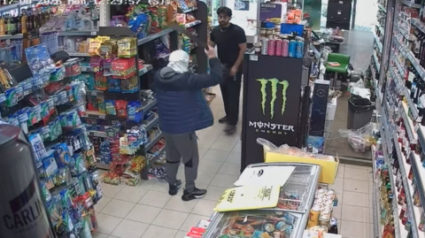 CCTV footage of a shop being robbed by a man with a knife in the air