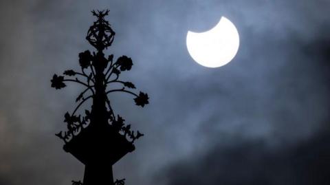 People watch the sky from Primrose Hill in north London as photographers aim cameras towards the horizon.