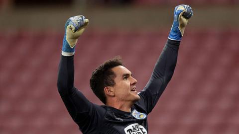 Huddersfield Town goalkeeper Lee Nicholls raises his arms in the air to celebrate with supporters after saving a Sunderland penalty in the Carabao Cup second round tie shoot-out.