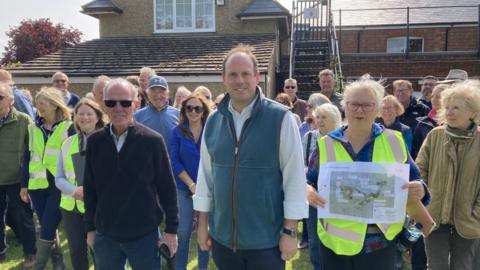 Group of people preparing to go on a demo walk, some wearing fluorescent jackets