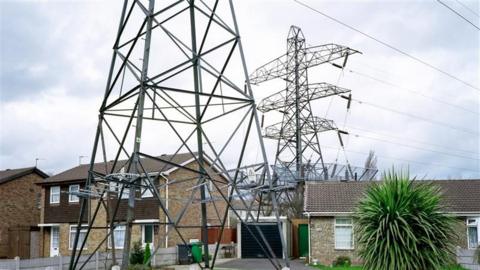 A pylon against a cloudy sky above two homes