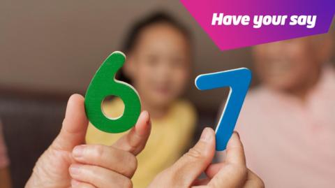 child holding a 6 and a 7 wooden number