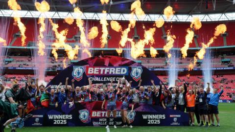 Wigan Warriors celebrate with the 2025 Women's Challenge Cup trophy after beating St Helens at Wembley Stadium