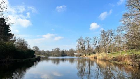 Blue sky with small fluffy white cloud above a boating lake 