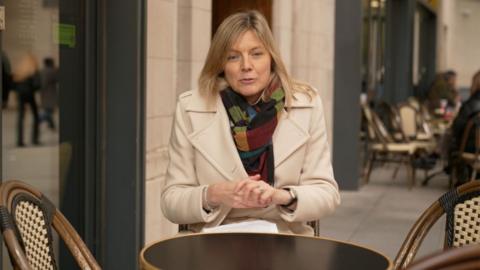 Ellie Price outside Cafe Nero in a colourful scarf and white jacket