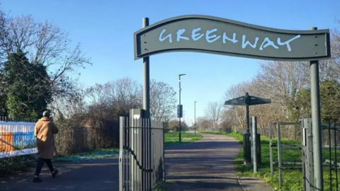 A view of the Greenway footpath with the name Greenway above an entrance and a passer-by walking along