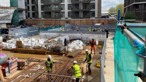 Builders in high vis jackets on a construction site in east London.