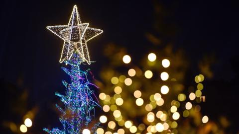 A lit up Christmas tree tip with a glowing star on the top