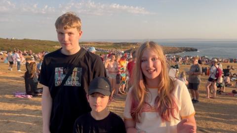 three children on a beach talking about the eclipse 