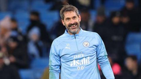 Scott Carson smiling in a Manchester City warm-up top