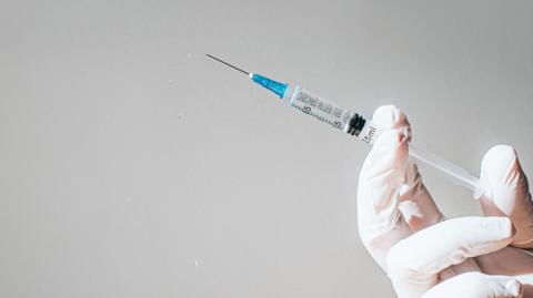 A hand holding a syringe