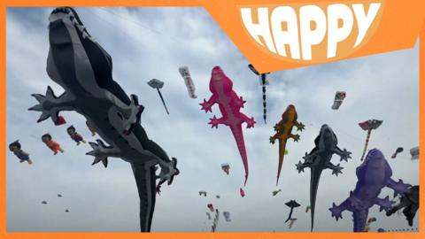 Animal kites in the sky and the Happy News logo
