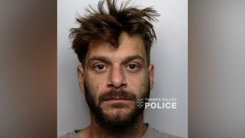 Custody photo of a man with messy dark brown hair and a beard
