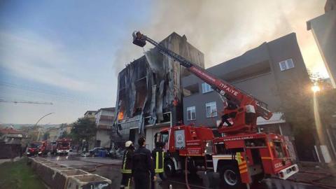 Firefighters on a cherry picker extinguish flames at the perfume warehouse