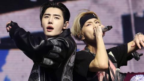 Sunghoon, with black hair and wearing a black leather jacket, and Jungwon, with blond hair, a black headband and a black T-shirt, of ENHYPEN perform at Sahara Tent during the 2025 Coachella Valley Music and Arts Festival 