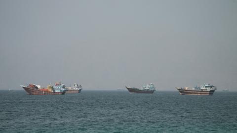 Four large boats drifting on the Strait of Hormuz as seen from Oman.