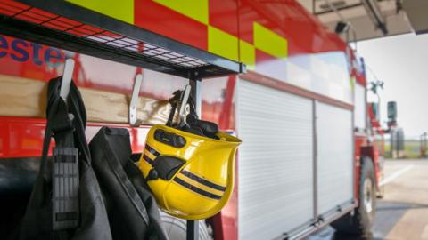 Firemans helmet hanging by fire engine in fire station - stock photo