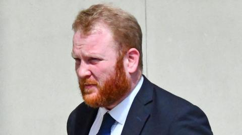 A man with a beard in a navy suit