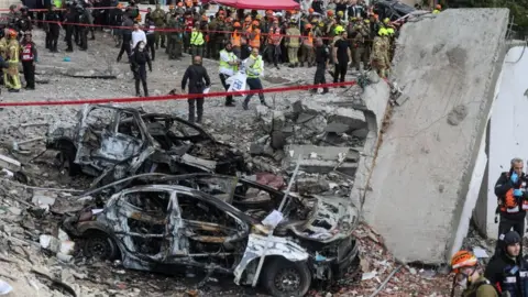 Emergency personnel work at the site of an Iranian strike, after Iran launched missile barrages following attacks by the U.S. and Israel on Saturday, in Beit Shemesh