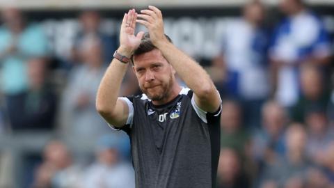 Darrell Clarke holds his hands above his head and claps as he walks on the pitch after a pre-season match