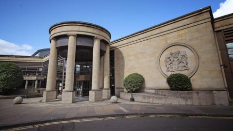 The exterior of the High Court in Glasgow, a large building with pillars at the entrance