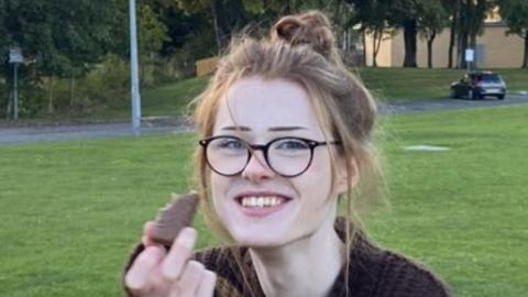 Brianna Ghey smiling while holding a chocolate snack at a park