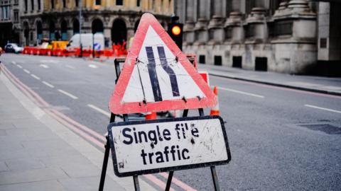 A road sign with notice of work in progress in a street in a city centre.