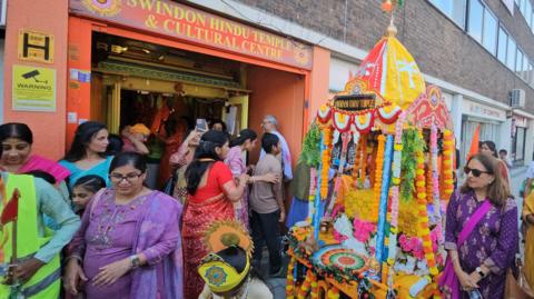 People are standing outside a Hindu temple in Swindon.
