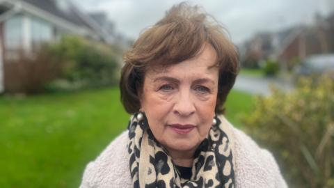 Diane Dodds wearing a cream coat with a light brown and black scarf. She has brown hair.