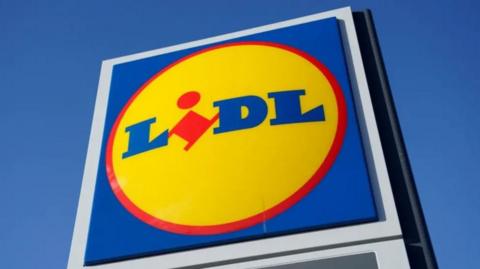 A large blue sign against a blue sign and there is a yellow circle in the middle of the sign with the word "lidl" written inside