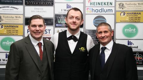 Three men in black suits. 