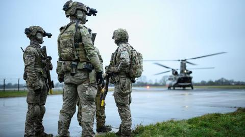 British special forces on a runway with a helicopter nearby