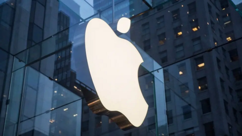 The Apple logo in front of a glass building 