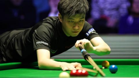 Zhao Xintong lines up a shot using a rest