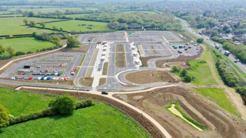 A bird's eye view of the Eynsham park and ride site, which is a large car park, built alongside the A40, which sits to the right of the picture.