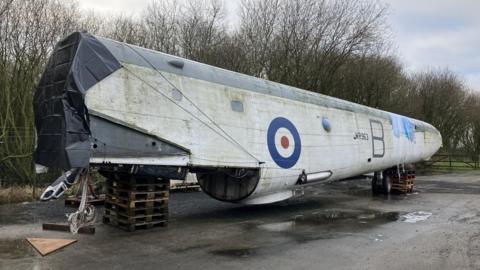 Piece of the plane from outside, it is white with the red and blue RAF logo. 